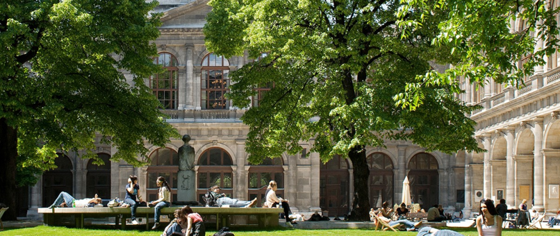 Arkadenhof der Universität Wien mit grünen Bäumen und Studierenden